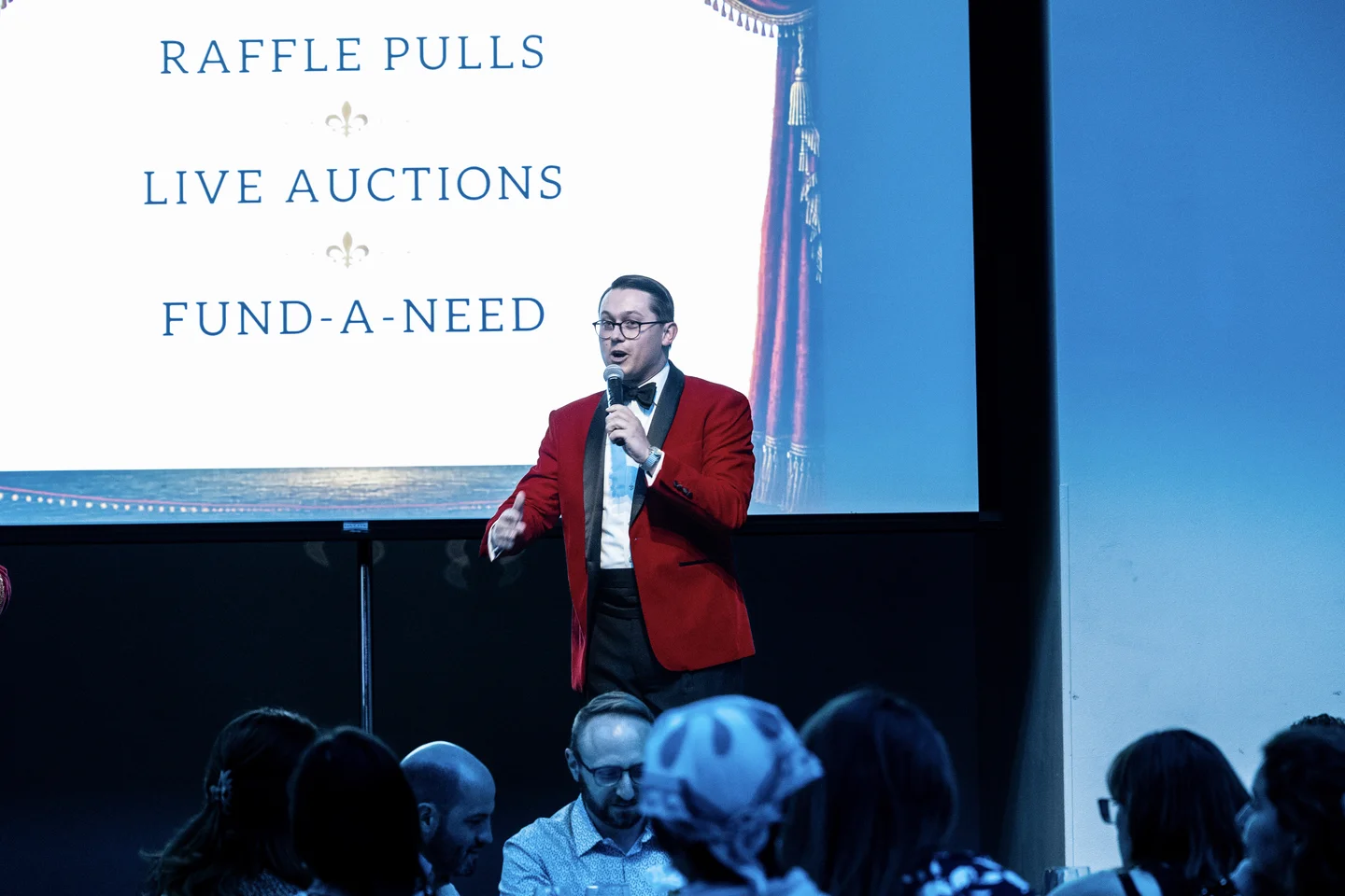 Tanner Beymer leading a live benefit auction with gala guests in the foreground