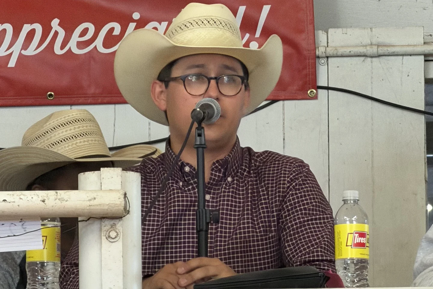 Tanner Beymer speaking into the microphone at a livestock auction