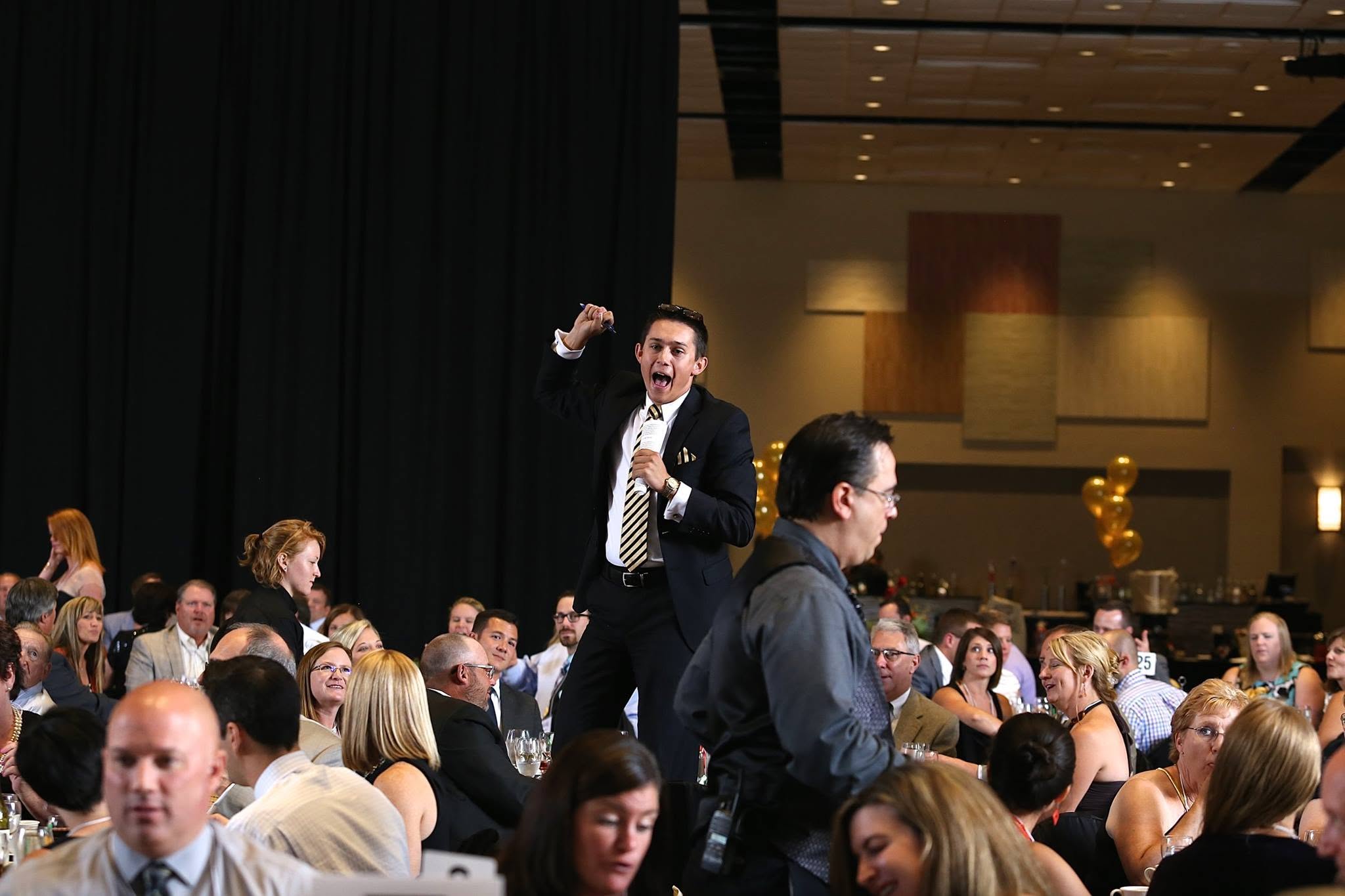 Auctioneer calling bids among guests at a benefit event